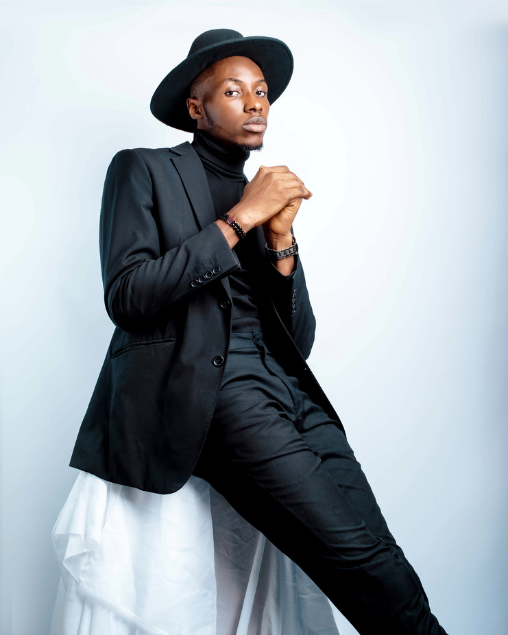 A Portrait of Male Model Wearing Black Suit and Hat During Photoshoot